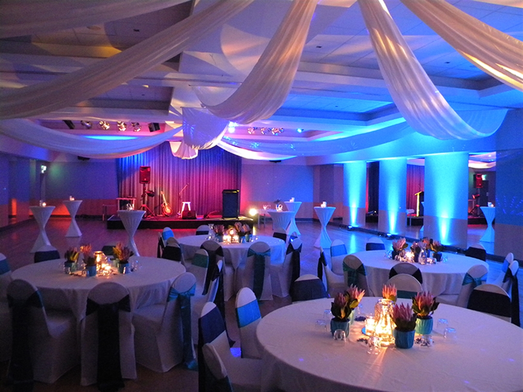 A hall dressed up for a private gathering with seated and standing tables